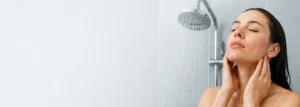 Woman enjoying a shower under a rainfall showerhead with water cascading over her face and neck.